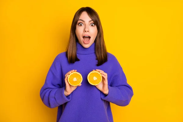 Portré vonzó csodálkozó vidám lány gazdaság narancssárga szeletek, mint a mell izolált felett élénk sárga háttér — Stock Fotó