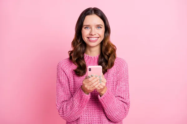 Retrato de atractiva chica de pelo ondulado alegre utilizando dispositivo de navegación aplicación web smm aislado sobre fondo de color pastel rosa —  Fotos de Stock