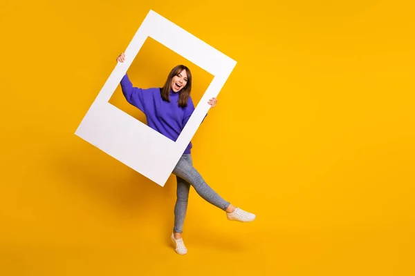 Foto di adorabile affascinante giovane donna indossare maglione viola ballare tenendo cornice bianca foto isolato colore arancione sfondo — Foto Stock