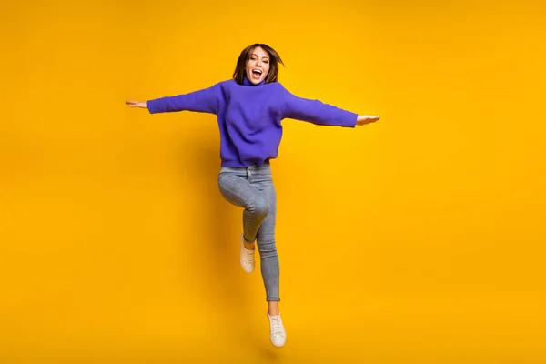 Photo of sweet funky young lady dressed violet sweater jumping hands arms sides isolated yellow color background — Stock Photo, Image