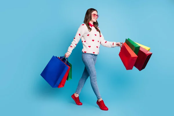 Ganzes Foto von glänzenden jungen Dame tragen Herzen drucken Pullover Brille zu Fuß Arme Schnäppchen isoliert blaue Farbe Hintergrund — Stockfoto