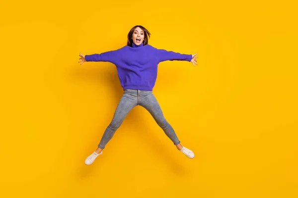 Photo of charming sweet young lady dressed violet sweater jumping like star isolated yellow color background — Stock Photo, Image