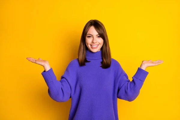 Foto de adorable joven bonita vestida suéter violeta mostrando escamas que sostienen el espacio vacío aislado de color amarillo de fondo —  Fotos de Stock