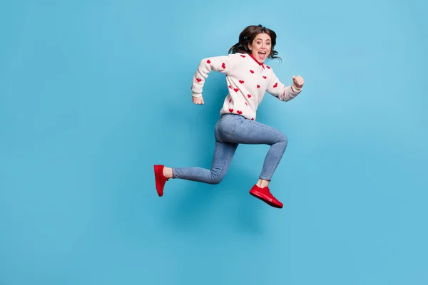 Foto de comprimento total de apressando alegre jovem senhora desgaste corações impressão suéter pulando correndo isolado azul cor fundo — Fotografia de Stock