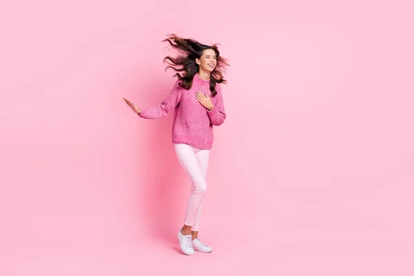Full size foto van hoera cool brunette dame staan kijken lege ruimte dragen roze trui broek sneakers geïsoleerd op roze achtergrond — Stockfoto