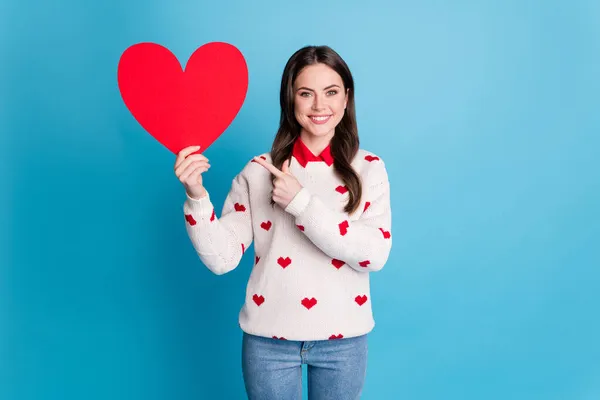 Фото блестящей очаровательной юной леди носить сердца печати свитер указывая держа большую бумагу сердце изолированный синий цвет фона — стоковое фото