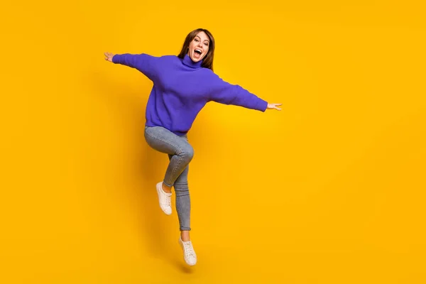 Foto de linda mujer joven divertida usar jersey púrpura saltar alto espacio vacío aislado color amarillo fondo — Foto de Stock