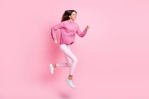 Foto de perfil de tamaño completo de optimista morena cool lady jump run use suéter rosa pantalones zapatillas aisladas sobre fondo rosa —  Fotos de Stock
