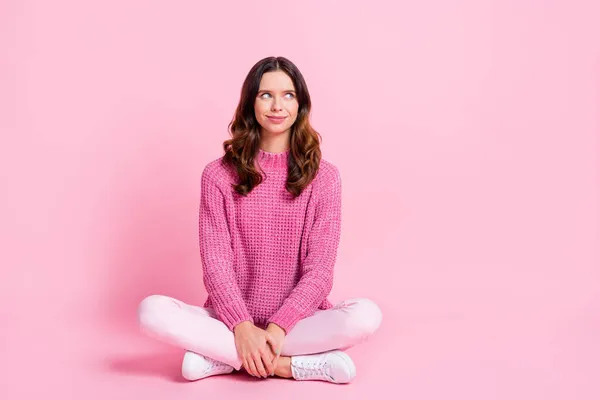 Full size photo of optimistic cool brunette lady sit look empty space wear pink sweater trousers sneakers isolated on pink background — Stock Photo, Image