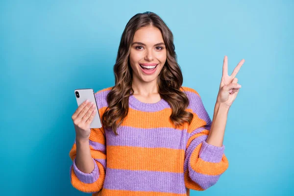 Fotografie atraktivní hezká hezká šťastná žena, aby v-sign hold telefon izolované na vložit modré barvy pozadí — Stock fotografie