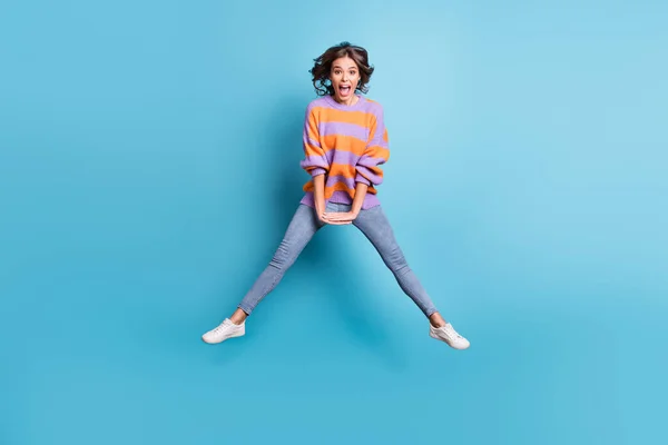 Фотографія повного тіла збудженої здивованої молодої людини стрибає з високим відкритим ротом ізольовано на синьому кольоровому фоні — стокове фото