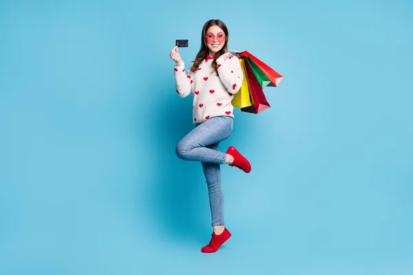Pleine longueur photo de jeune femme habillé coeurs imprimer pullover lunettes armes boutique sacs carte bancaire isolé fond de couleur bleue — Photo