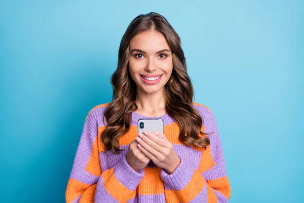 Foto van mooie dame houden telefoon kijken camera tand glimlach dragen gestreepte trui geïsoleerde blauwe achtergrond — Stockfoto
