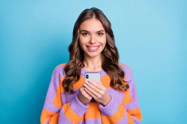 Foto de senhora bonita segurar telefone olhar câmera toothy sorriso desgaste listrado pulôver isolado fundo azul — Fotografia de Stock