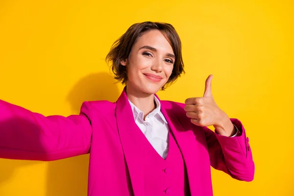 Foto de adorável brilhante jovem senhora desgaste rosa terno sorrindo gravação auto vídeo mostrando polegar para cima isolado cor amarela fundo — Fotografia de Stock