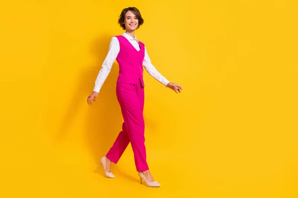 Full size photo of optimistic young brunette lady go wear pink suit stilettos isolated on yellow background — Stock Photo, Image