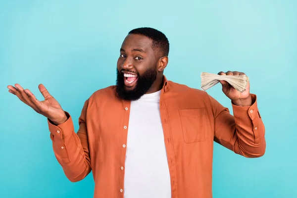 Fotografie mladého afro business muž šťastný pozitivní úsměv držet peníze peníze bohaté izolované přes tyrkysové barvy pozadí — Stock fotografie