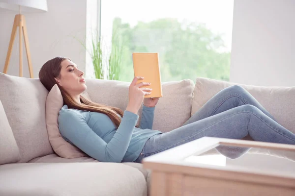Profil boczne zdjęcie młodej atrakcyjnej kobiety leżącej sofa komfort przytulny czytać książki literatura powieść weekend dom — Zdjęcie stockowe