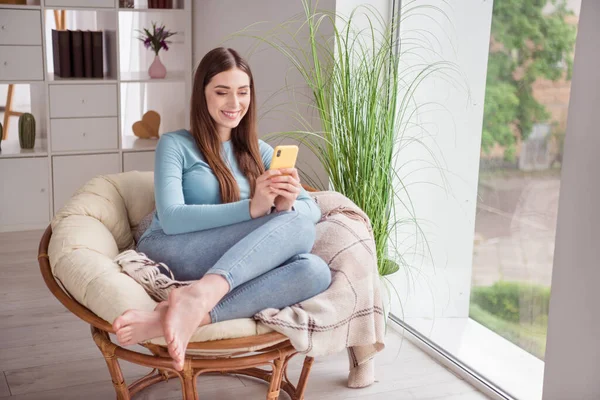 Foto portret jonge vrouw zitten in fauteuil glimlachen gelukkig browsen internet met smartphone — Stockfoto