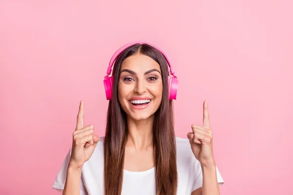 Foto da jovem morena legal ouvir música apontar para cima desgaste branco t-shirt isolado no fundo cor-de-rosa — Fotografia de Stock