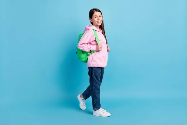 Full body profile photo of optimstic cute long hair girl go wear bag sweatshirt isolated on blue background — Stock Photo, Image