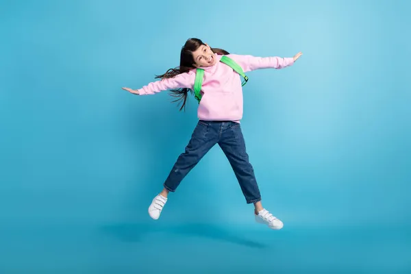 Foto de linda encantadora niña de la escuela usar sudadera rosa bolso de escuela saltando alto como la estrella aislado fondo de color azul — Foto de Stock