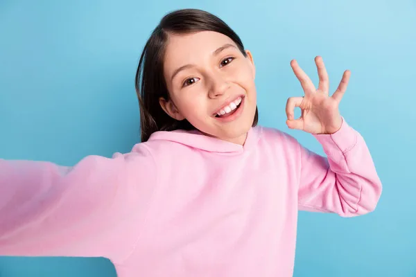 Foto de menina cabelo longo otimista fazer selfie mostrar okey usar camisola rosa isolado no fundo azul — Fotografia de Stock
