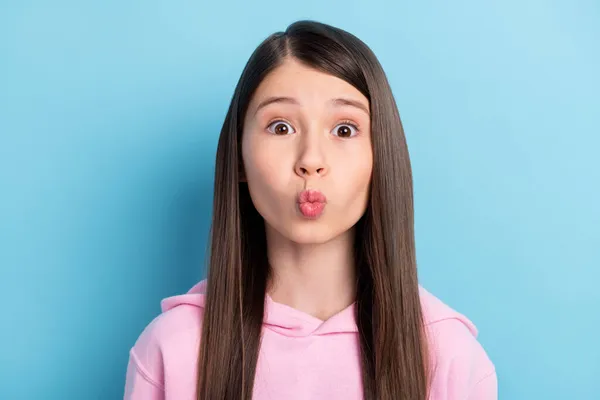 Porträtt av roliga söta långt hår flicka blåsa kyss bära rosa tröja isolerad på klarblå färg bakgrund — Stockfoto
