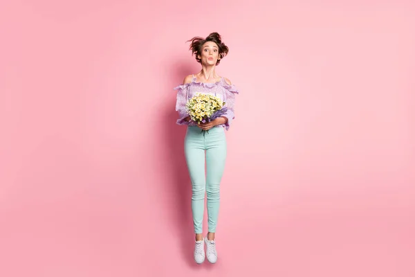 Photo of lady jump hold virágok küld levegő csók viselni lila blúz nadrág tornacipő elszigetelt rózsaszín szín háttér — Stock Fotó