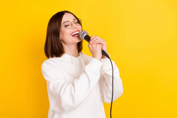 Foto di bella signora tenere microfono cantare hit canzone usura specifiche bianco felpa isolata colore giallo sfondo — Foto Stock