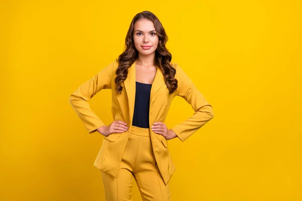 Porträtt av attraktiva glada vågiga hår kvinna regissör agent händer på höfter poserar isolerade över ljusa gula färg bakgrund — Stockfoto