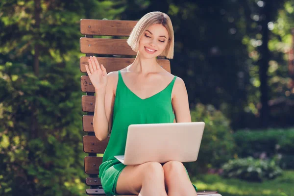 Photo de convivial sociable femme d'affaires tenir ordinateur portable réunion à distance assis banc porter robe verte ville urbaine à l'extérieur — Photo
