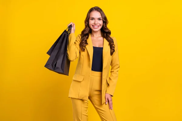 在鲜活的黄色背景下 一个漂亮而快乐的 波浪形头发的女人抱着购物袋的画像被隔离了起来 — 图库照片
