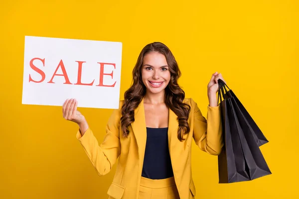 Foto van charmante aantrekkelijke jonge dame dragen pak jas met koopjes verkoop kaart glimlachen geïsoleerde gele kleur achtergrond — Stockfoto