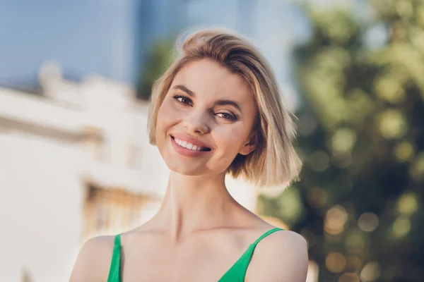 Fénykép aranyos bájos fiatal hölgy visel zöld ruhát séta mosolygós kívül városi utcában — Stock Fotó