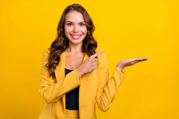 Portret bardzo wesołej kobiety z falowanymi włosami, trzymającej dłoń, demonstrującej reklamę miejsca odizolowanego na jaskrawym żółtym tle. — Zdjęcie stockowe