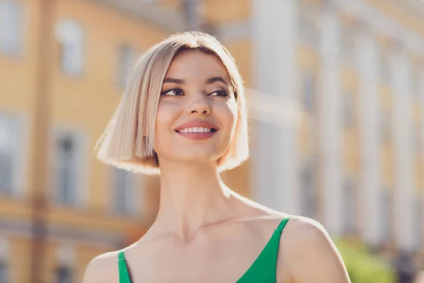 Zdjęcie uroczej, marzycielskiej młodej damy w zielonym stroju, uśmiechniętej spacerującej cieszącej się słońcem poza ulicą miejską. — Zdjęcie stockowe