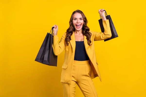 Portré vonzó vidám hullámos hajú nő gazdaság táskák új dolgok szórakozás örvendezik elszigetelt felett ragyog sárga színű háttér — Stock Fotó