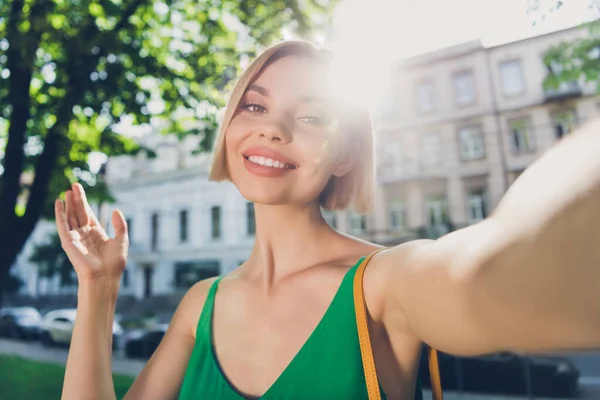 Foto de adorável doce jovem senhora usar roupa verde bolsa sorrindo andando selfie tacking fora da rua urbana da cidade — Fotografia de Stock