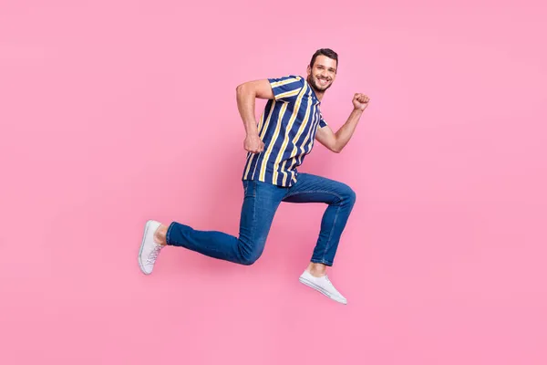 빠른 젊은 브루 넷 선수가 뛰고 있는 사진 전체 크기는 핑크 배경에서 분리 된 티셔츠 청바지 운동화를 신고 있다. — 스톡 사진