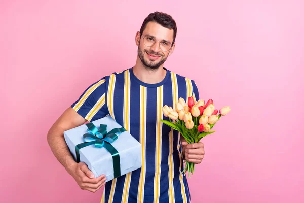 Foto portret man in bril houden geschenk tulpen boeket geïsoleerde pastel roze kleur achtergrond — Stockfoto