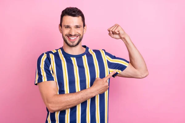 Фотопортрет мужчина улыбается указывая пальцем сильные бицепсы изолированные пастельно-розовый цвет фона — стоковое фото