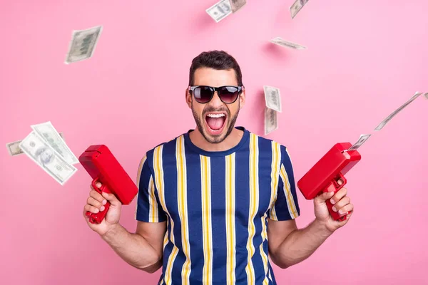 Foto retrato hombre en gafas de sol disparando billetes en el aire aislado pastel de color rosa de fondo — Foto de Stock