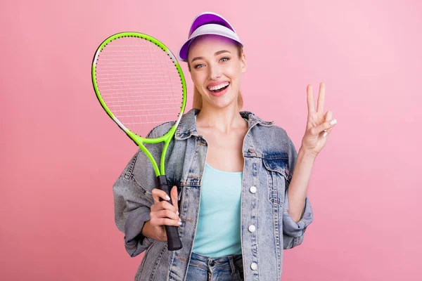 Foto van coole jonge sportieve dame hold racket show v-teken slijtage jeans shirt cap geïsoleerd op roze kleur achtergrond — Stockfoto