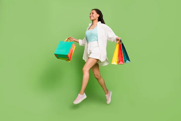 Ganzkörpergröße Foto Frau halten Taschen springen läuft in Einkaufszentrum isoliert pastellgrüne Farbe Hintergrund — Stockfoto