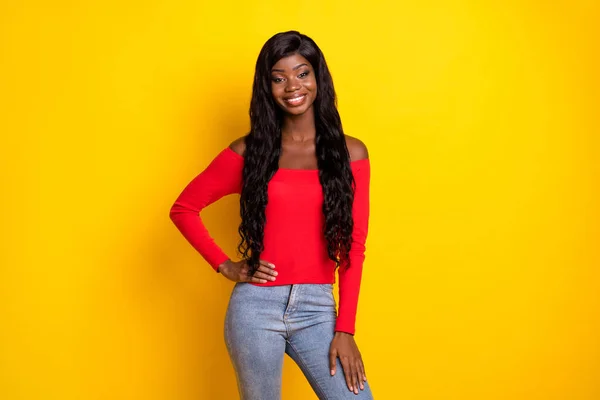 Photo of pretty sweet dark skin girl dressed red top arm waist standing isolated yellow color background.