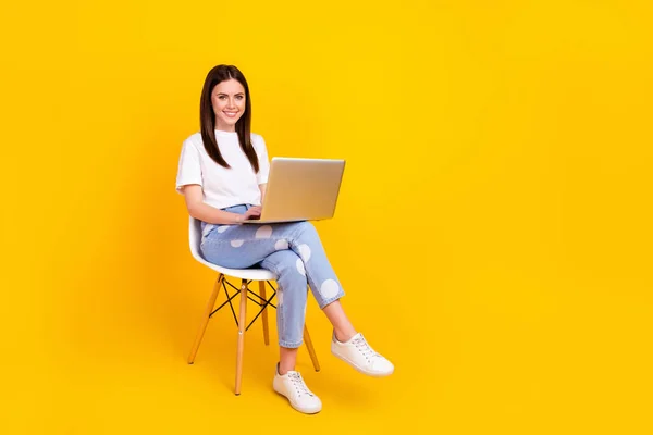 Πλήρες μέγεθος προφίλ πλευρά φωτογραφία της νεαρής γυναίκας χαρούμενο χαμόγελο κάθονται καρέκλα εργασίας laptop chat τύπος ηλεκτρονικού ταχυδρομείου που απομονώνονται σε κίτρινο χρώμα φόντο — Φωτογραφία Αρχείου