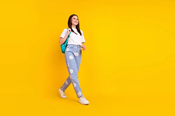 フルボディプロフィール側の写真の若い魅力的な女の子幸せな正の笑顔行くステップバックパック隔離された黄色の色の背景 — ストック写真