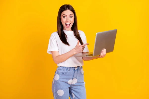 Foto de menina feliz sorriso positivo apontar dedo laptop escolha conselho sugerir isolado sobre fundo de cor amarela — Fotografia de Stock