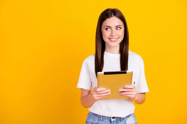 Fotografie mladé dívky šťastný pozitivní úsměv držet tablet gadget vypadat prázdný prostor izolované přes žlutou barvu pozadí — Stock fotografie